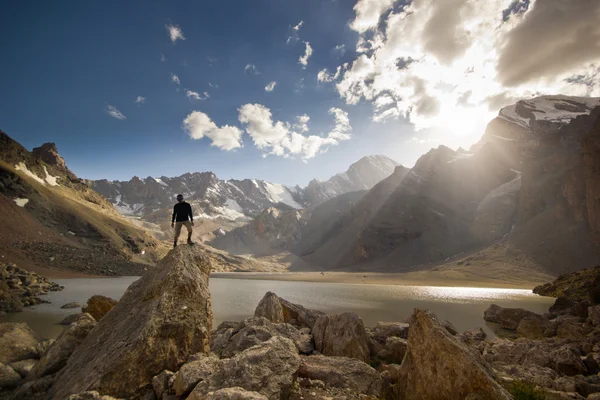 Man on a cliff at sunset near the mountain lake — Stock Photo, Image