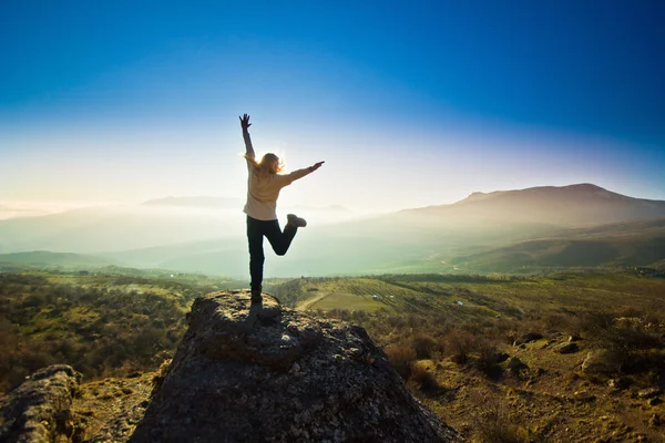 Girl with hands up in the mountains against sun — Stock Photo, Image