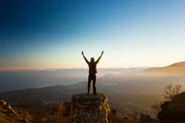 Man with hands up in the mountains against sun — Stock Photo, Image