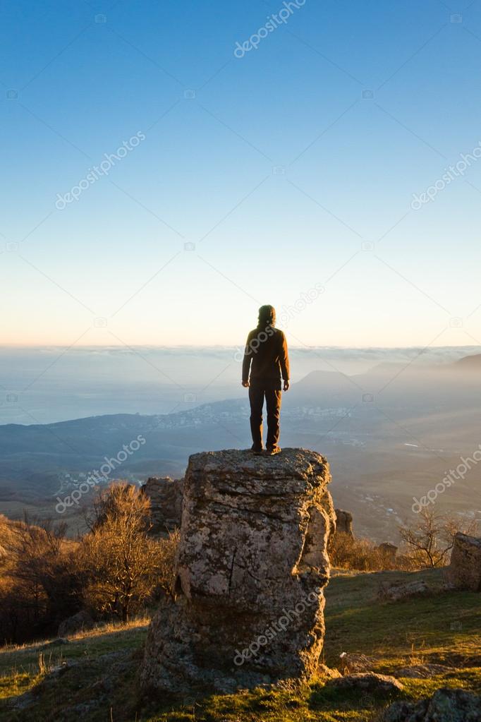 man on the cliff in mountains at sunset
