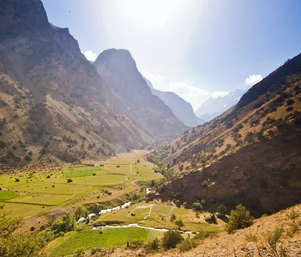 Mountain valley with blue river and sun above — Stock Photo, Image
