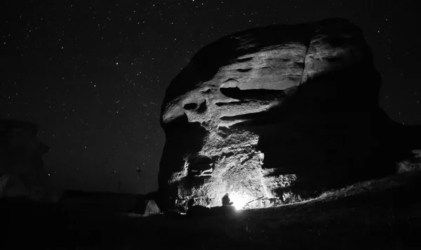 Bounfire fények ülő ember nagy szikla — Stock Fotó
