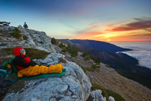 Chica sentada en un acantilado en las montañas al amanecer — Foto de Stock