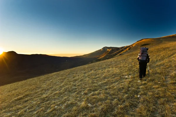 Menina solitária caminhadas nas montanhas ao nascer do sol — Fotografia de Stock