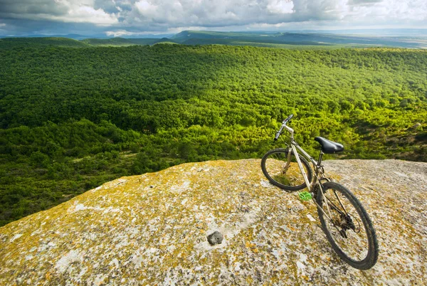 Vélo sur une falaise couverte de collines forestières — Photo