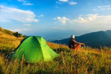 dağlarda çadır yakın oturan adam