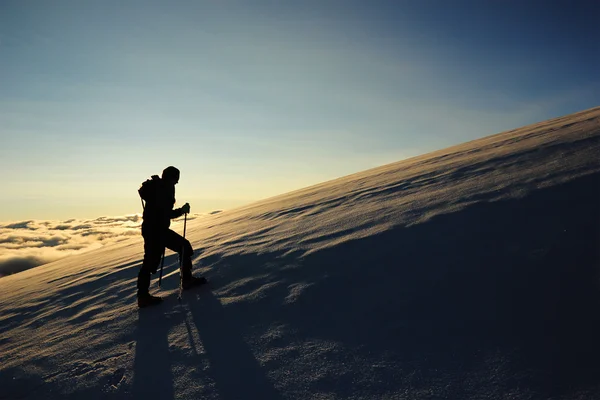 girl goes on a snowy slope in the mountains against sun