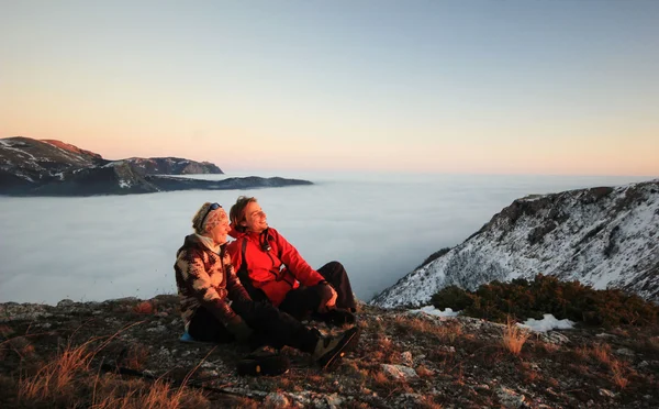 冬の夕暮れ時、山の上に座ってカップル — ストック写真