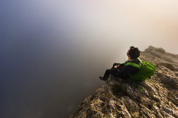 Man sitter på en klippa i dimmigt väder — Stockfoto