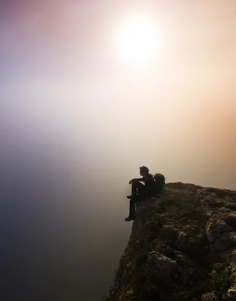 Man sitter på en klippa i dimmigt väder — Stockfoto