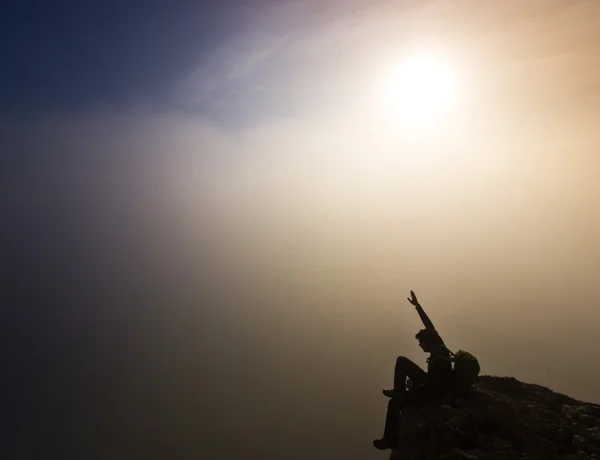 Mann sitzt bei nebligem Wetter auf einer Klippe — Stockfoto