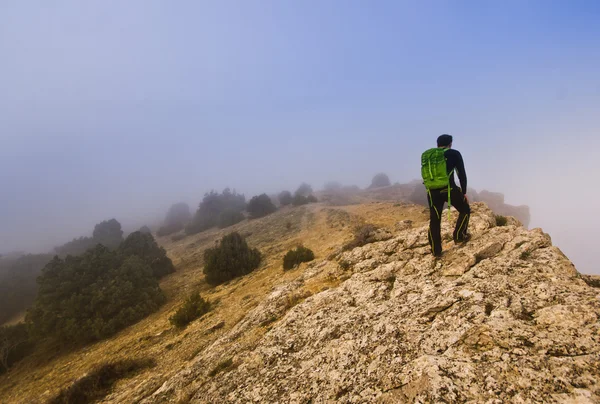 Mann läuft bei nebligem Wetter am Rande einer Klippe — Stockfoto