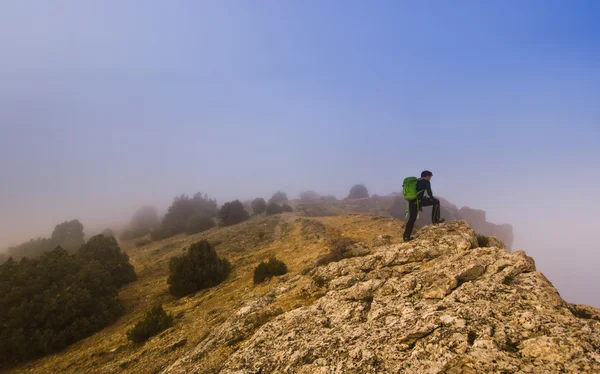 Hombre caminando en el borde de un acantilado en el tiempo brumoso —  Fotos de Stock