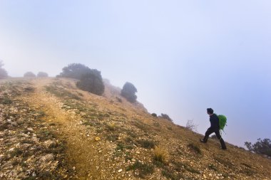 sisli havalarda bir uçurumun kenarında yürüyen adam