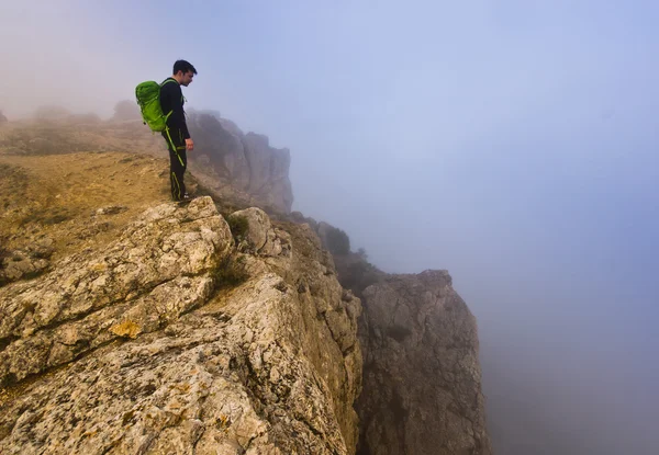 Man standing on a cliff in foggy weather — Stock Photo, Image