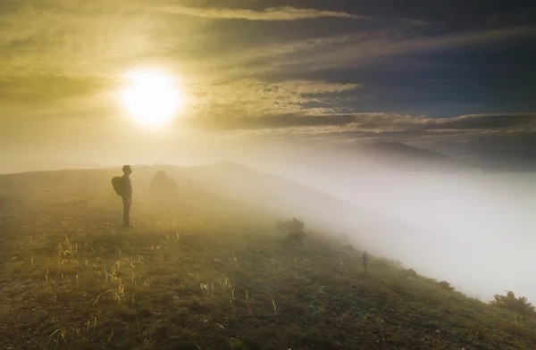 Mann steht bei Sonnenuntergang im Nebel auf einem Hügel — Stockfoto