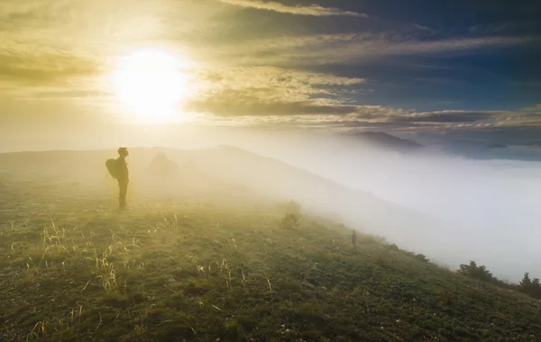 Man die op een heuvel in mistig weer bij zonsondergang — Stockfoto
