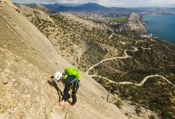 kaya tırmanışçısı dağ deniz ile arka plan üzerinde tırmanıyor.