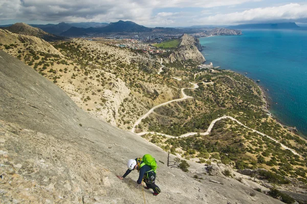 Bergsteiger besteigt Berg mit Meer im Hintergrund — Stockfoto