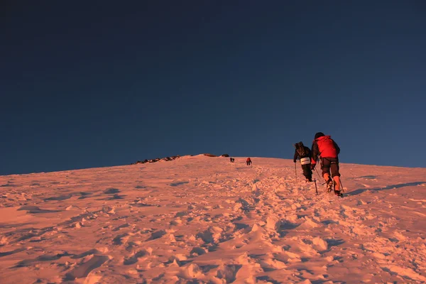 Escaladores caminando en la cima de la montaña al amanecer — Foto de Stock