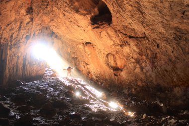 küçük insan ve içindeki güneş ışınları ile büyük mağara