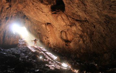 küçük insan ve içindeki güneş ışınları ile büyük mağara