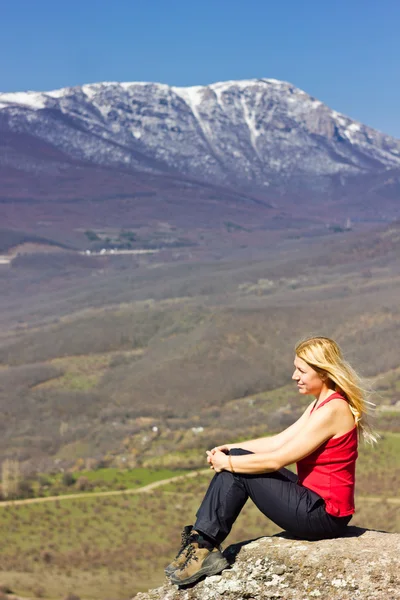Дівчина сидить на скелі в горах — стокове фото