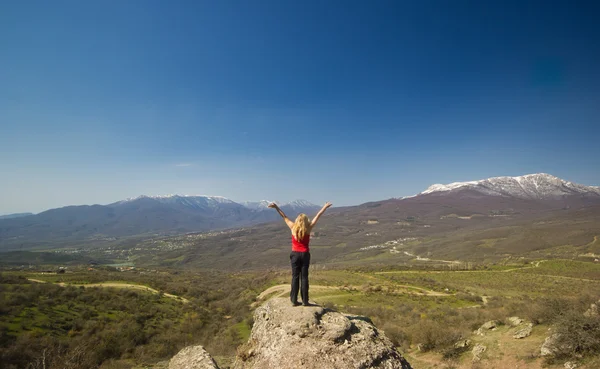 Girl with hands up in the mountains against sun — Stock Photo, Image