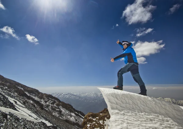 Hombre de pie en una cornisa de nieve en la salida del sol de montaña — Foto de Stock
