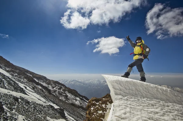 Homem de pé em uma cornija de neve no nascer do sol da montanha — Fotografia de Stock