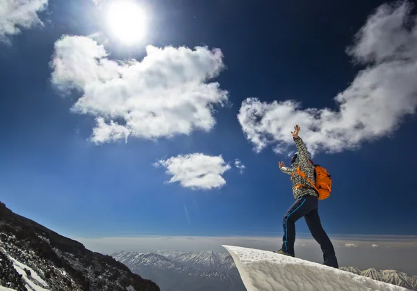 Homem de pé em uma cornija de neve no nascer do sol da montanha — Fotografia de Stock