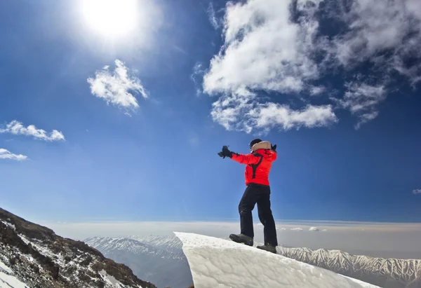Homem de pé em uma cornija de neve no nascer do sol da montanha — Fotografia de Stock