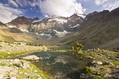 gün batımında yüksek tepeler tarafından çevrili mavi dağ gölü