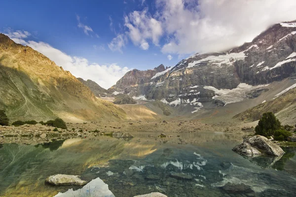 Голубое горное озеро, окруженное высокими вершинами на закате — стоковое фото