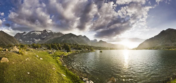 Gün batımında yüksek tepeler tarafından çevrili mavi dağ gölü — Stok fotoğraf