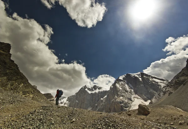 Hombre en un acantilado al atardecer rodeado de montañas — Foto de Stock