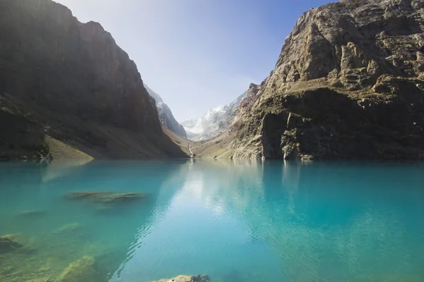 Mavi dağ gölü yüksek kayalar yansıtır — Stok fotoğraf