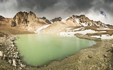 gün batımında yüksek tepeler tarafından çevrili mavi dağ gölü