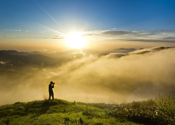 Man på en kulle vid solnedgången med kameran att göra Foto — Stockfoto