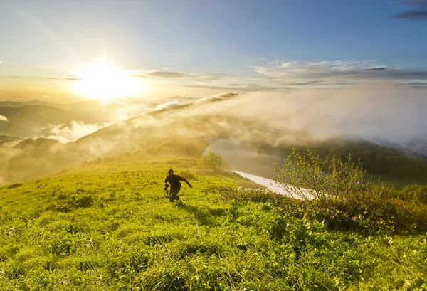 Человек бежит по холму на закате с фотоаппаратом — стоковое фото