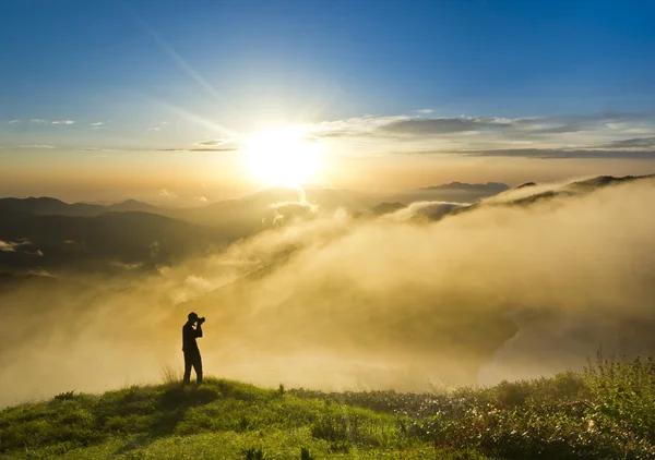 Man på en kulle vid solnedgången med kameran att göra Foto — Stockfoto