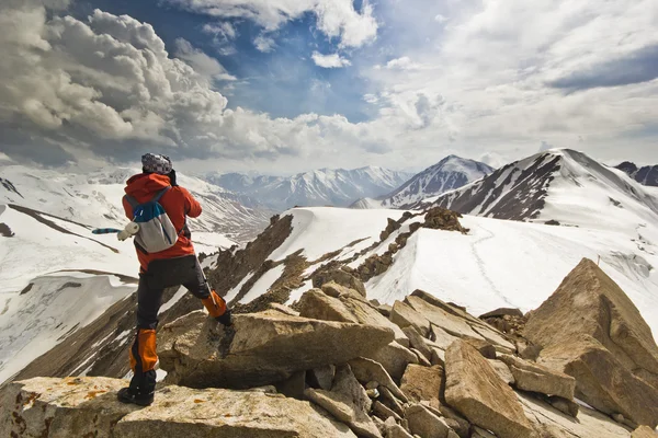 Человек, стоящий на скале в горах с шестом — стоковое фото