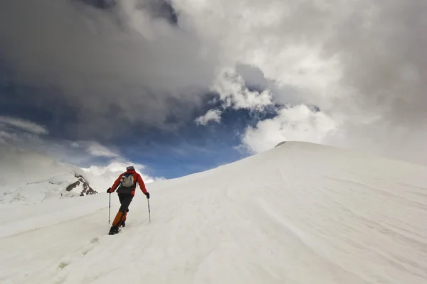 男の棒で雪の山に登る — ストック写真