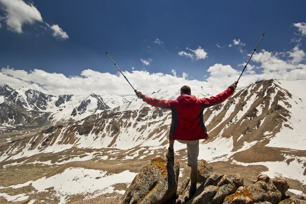 Man standing on a cliff in mountains with poles — Stock Photo, Image