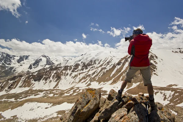 Hombre en un acantilado en las montañas haciendo foto — Foto de Stock