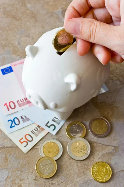 Billetes y monedas en euros con alcancía —  Fotos de Stock