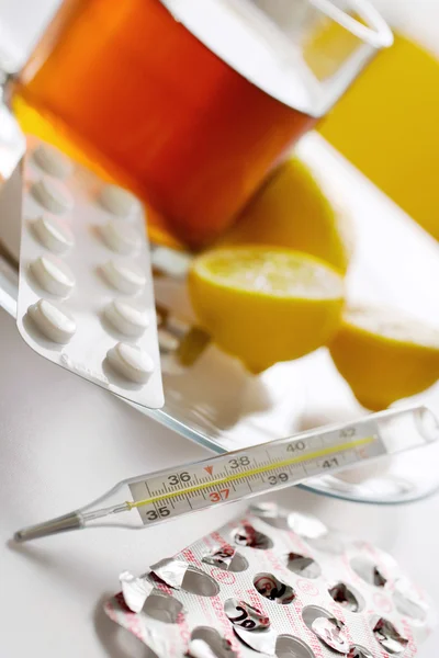 Черный чай со свежими лимонами и таблетками от гриппа в блистере с термометром — стоковое фото