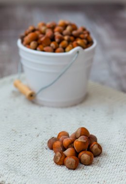 Ahşap arka plan üzerinde beyaz bir kova içinde fındık