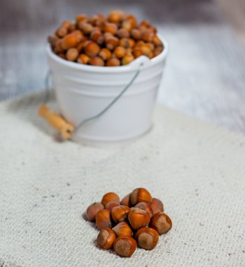 Ahşap arka plan üzerinde beyaz bir kova içinde fındık