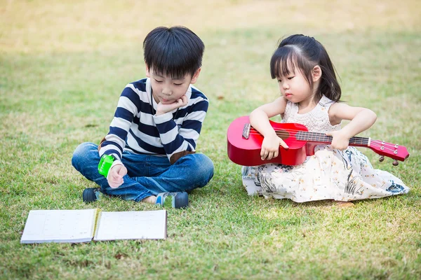Brother and sister play guitar in the garden — Stock Photo, Image